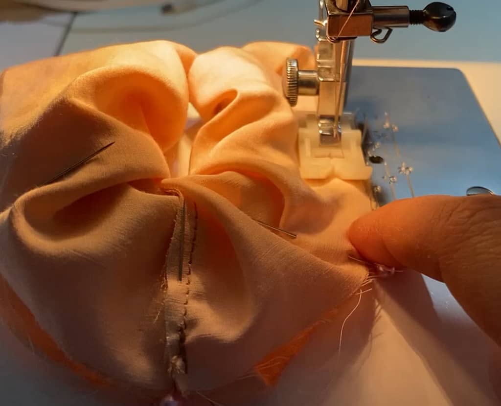 close up of sewing machine foot sewing red silk scrunchie 
