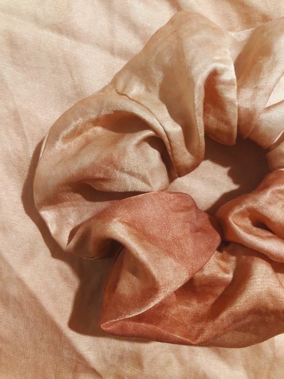 close up of red silk scrunchie laying on red silk fabric